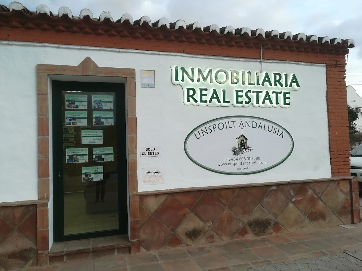 The exterior of Unspoilt Andalusia features a white wall with a green door and illuminated signage.
