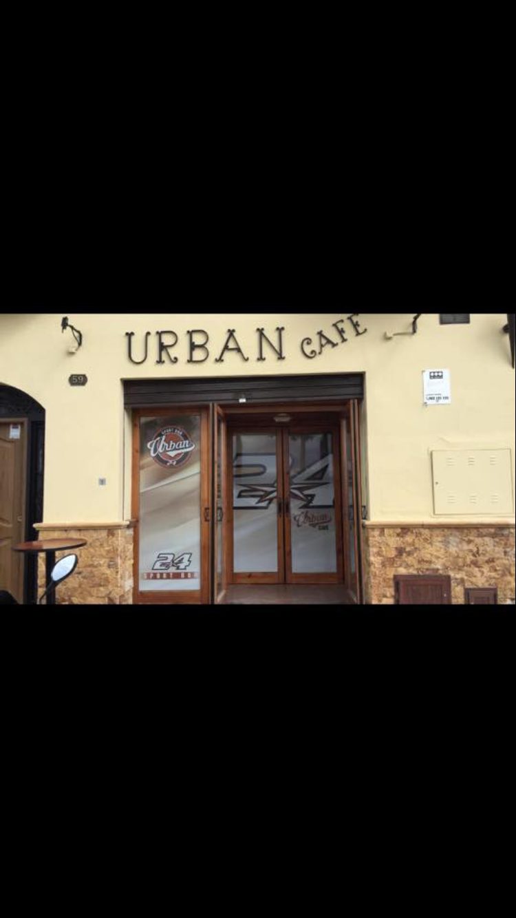 The entrance of Urban Café features a wooden door and a stylish sign above.