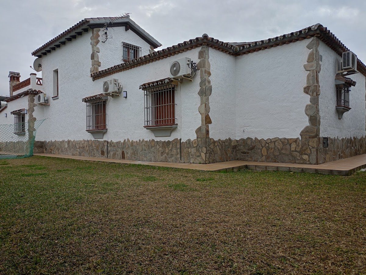 Villa Family cuenta con un espacioso edificio blanco con detalles de piedra y una zona ajardinada.