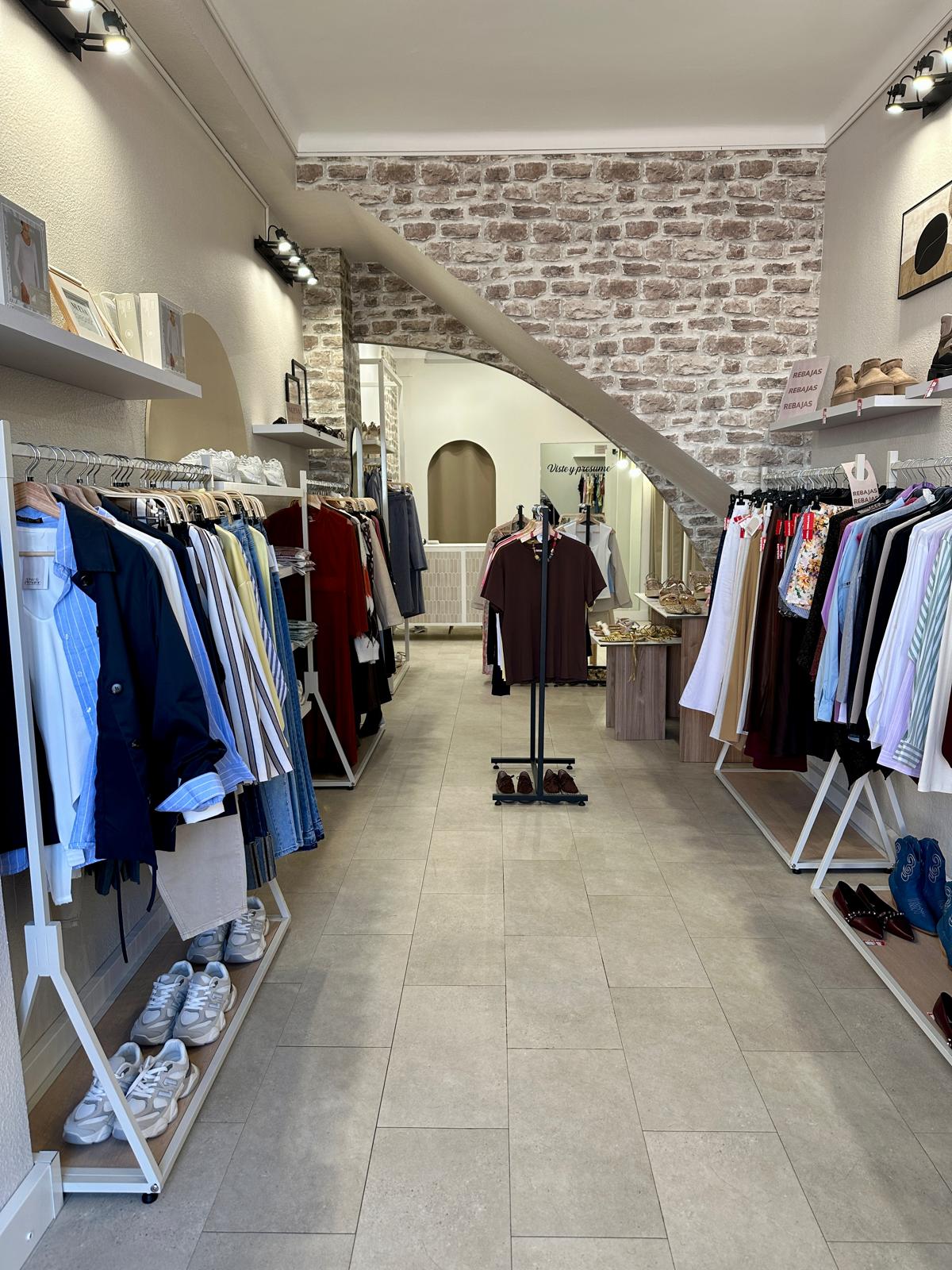 A stylish interior of Viste y Presume featuring clothing racks and a modern design.