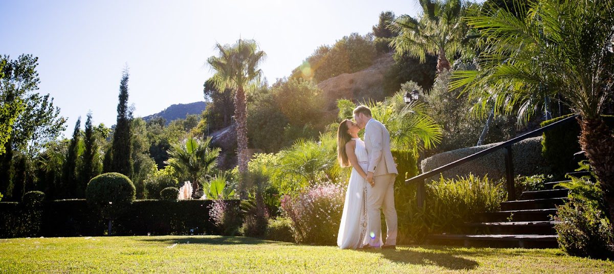 A couple embraces in a lush garden surrounded by palm trees at Wedding Service Spain in Manilva.
