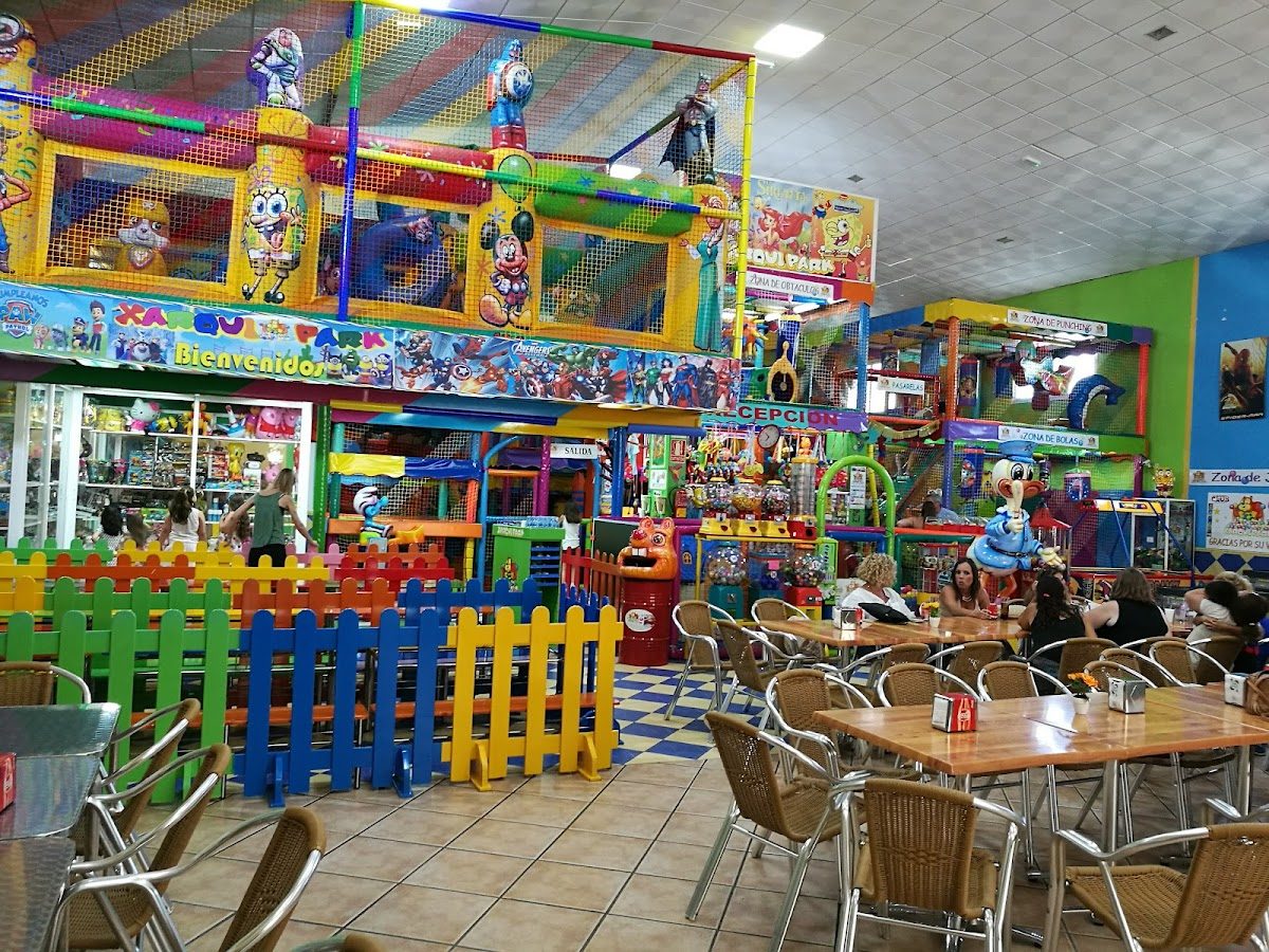 Colorful indoor play area with climbing structures, games, and seating for families at Xarqui Park.