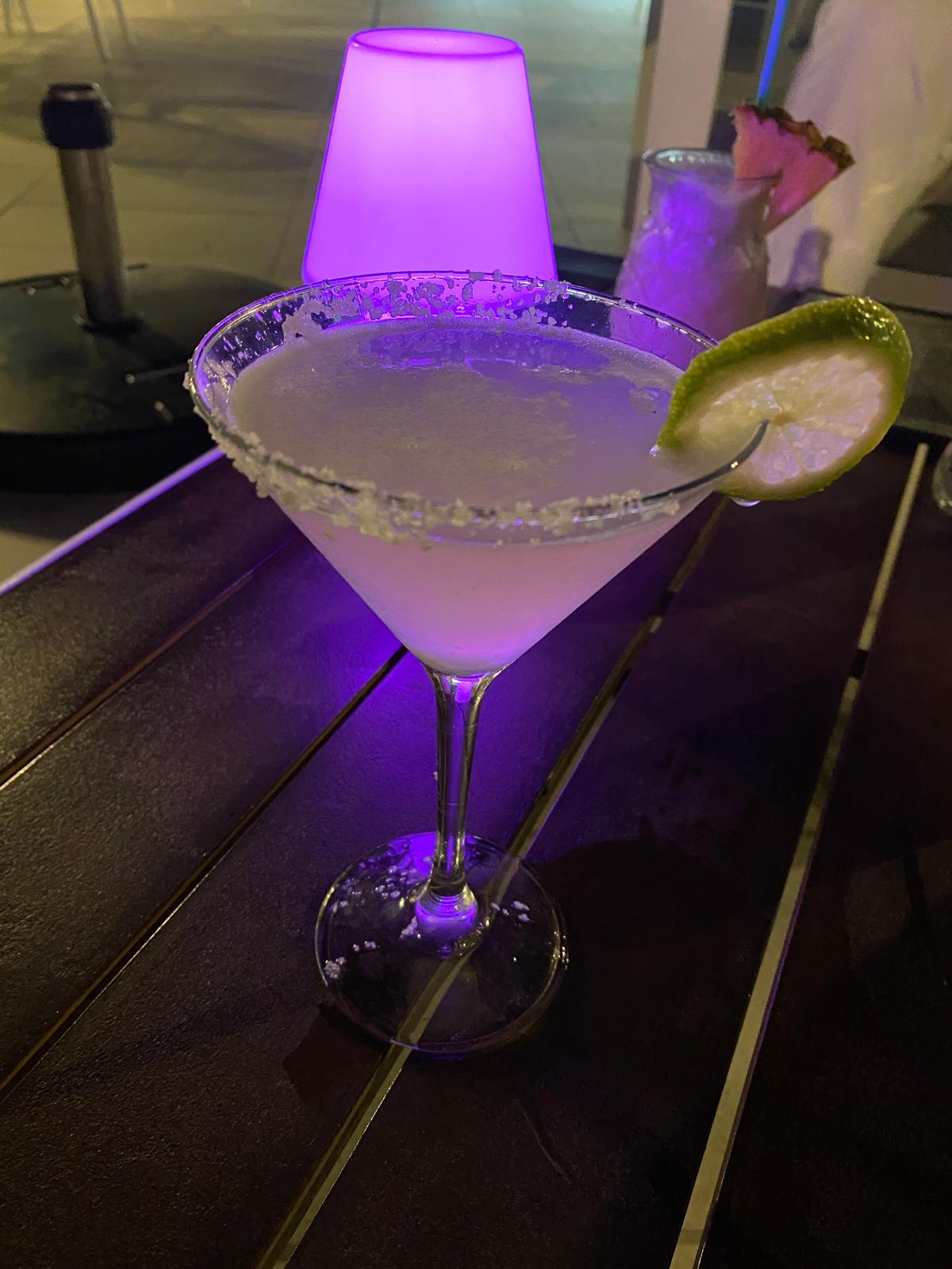 A cocktail with a lime wedge and salt rim served on a table at Yesca Rooftop.